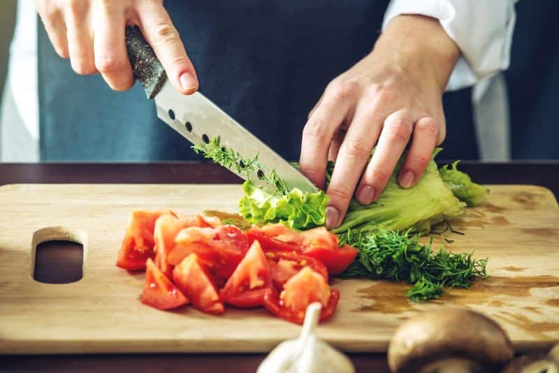 view of cutting board with tomato and lettuce being sliced