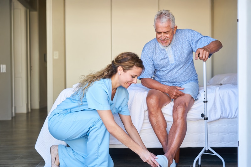 Female nurse helping a male patient put on his shoes