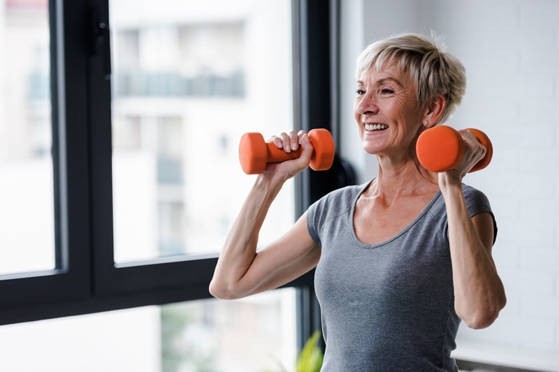 Woman exercising with weights and smiling