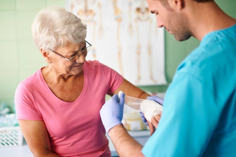 Nurse wrapping wound on patient's hand